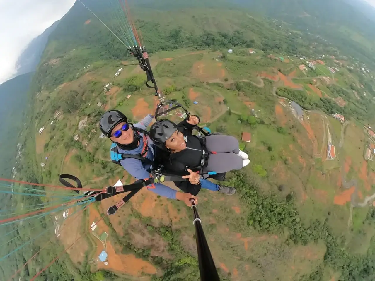 A tandem paragliding flight high above the green hills of the Cauca Valley.
